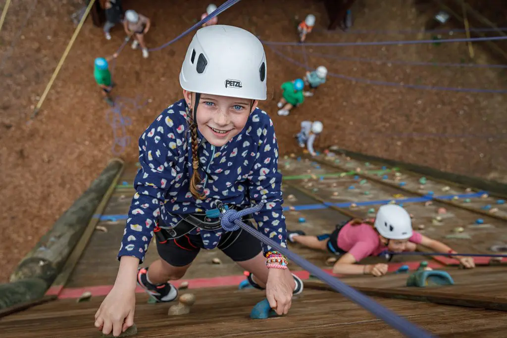 school group climbing up a climbing wall