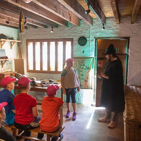 barley hall tour guide dressed in Elizabethan clothing demonstrating to school pupils