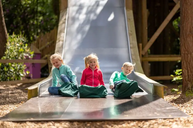 3 primary school students going down a big slide all together