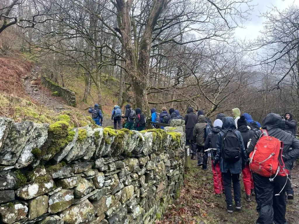 school group walking along a muddy track in a wooded area