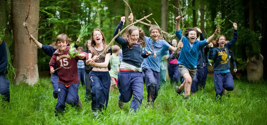 The Bushcraft Company at Penshurst Place Kent 9 school group in a forest running with sticks
