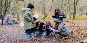 pupils in the woods starting a camp fire