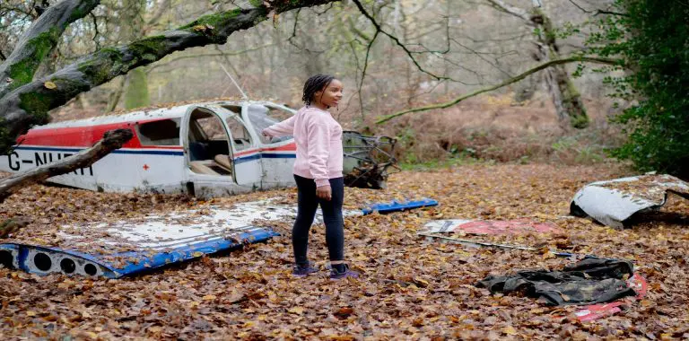 school pupil in woods near some old plane wreckage
