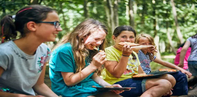 school group around camp area eating food