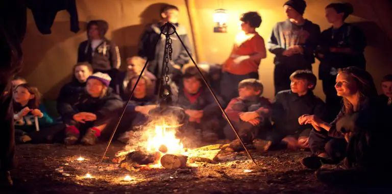 School group sat around camp fire at night
