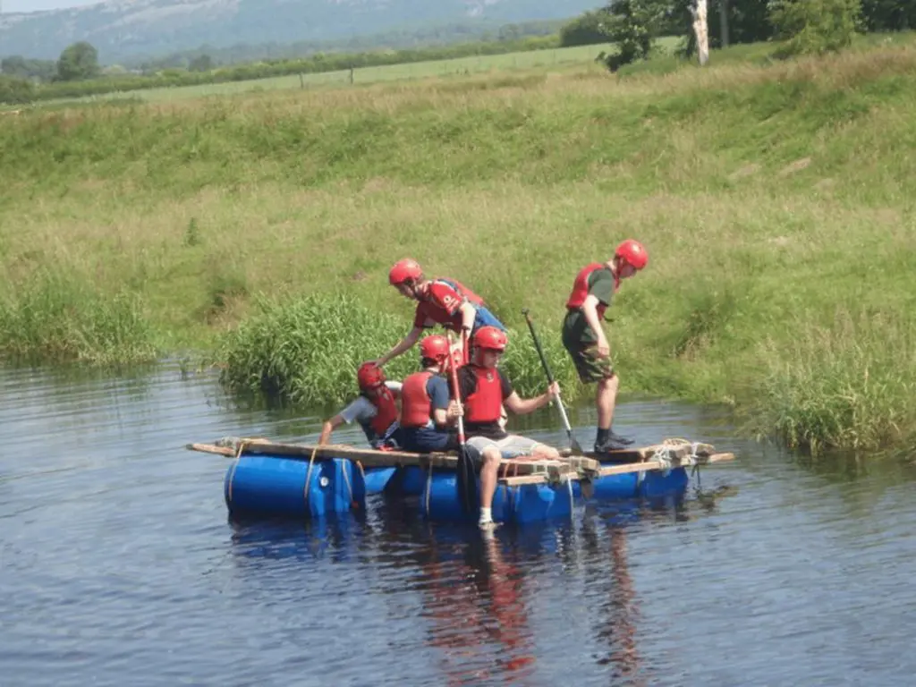 school group with lifejackets hard hats on a raft in a lake in Cumbria