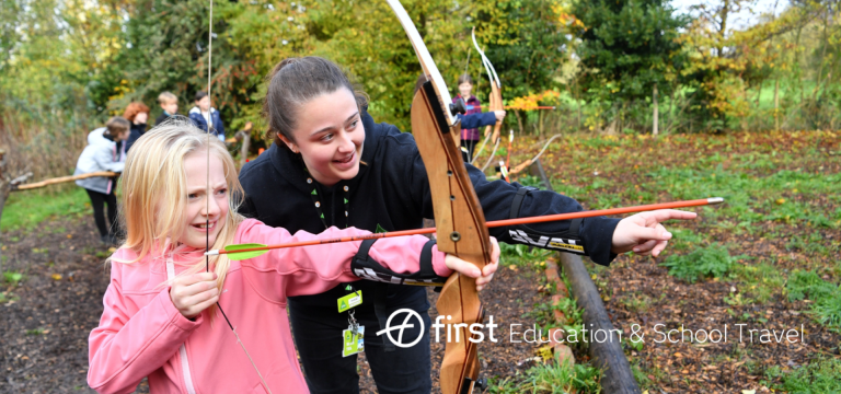 school pupil with instructor on an archery range