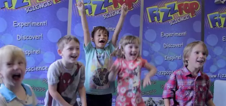 primary school students jumping up with excitement and happy faces at a science workshop