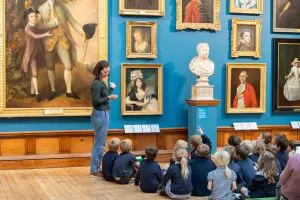 school group with museum tour person showing art work