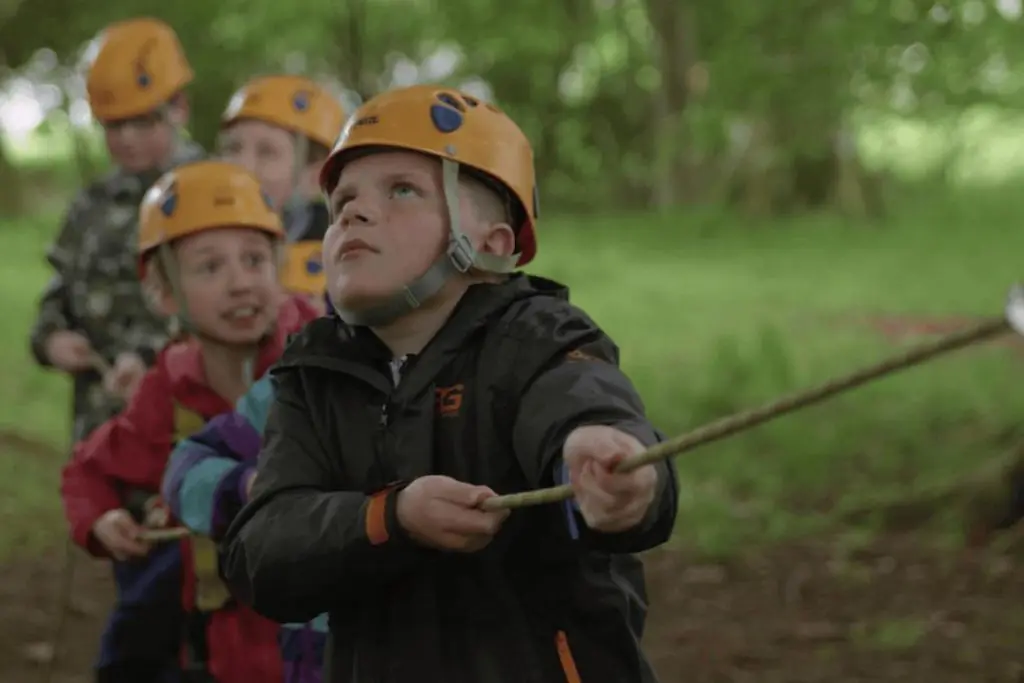 school pupils in hard hats pulling a rope challenge