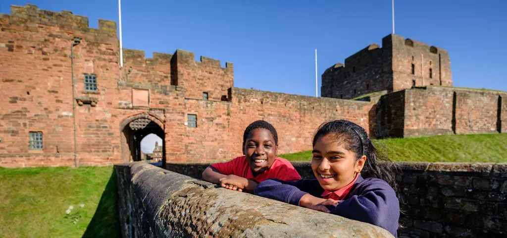 English Heritage North West 9 two school pupils smiling outside at a castle grounds near the keep