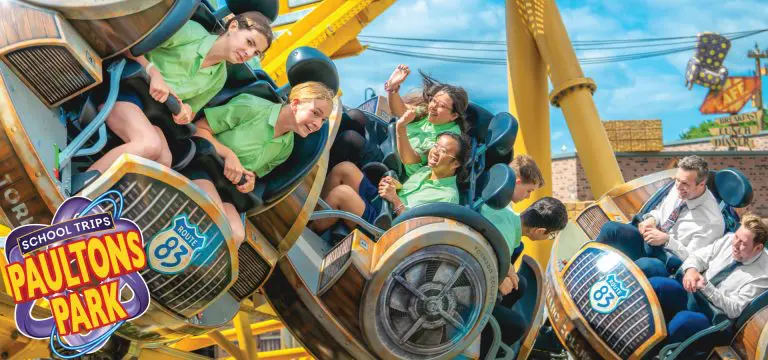 school group including a teacher enjoying a fast moving theme park ride
