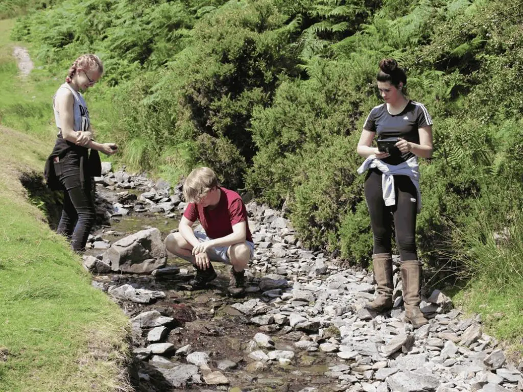 three post 16 school students doing eco river study field work