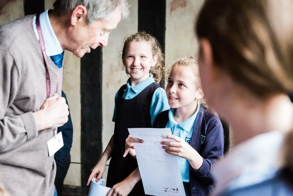 school pupil handing an information sheet to a learning provider at the Shakespeare schoolroom and guildhall