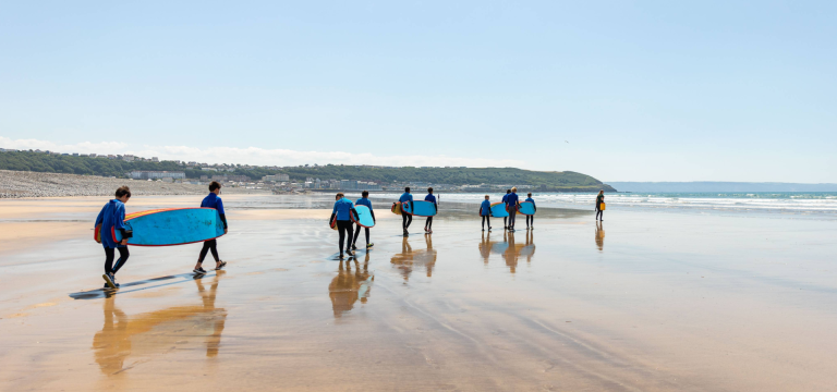 school students on beach ready to do surfing in the sea