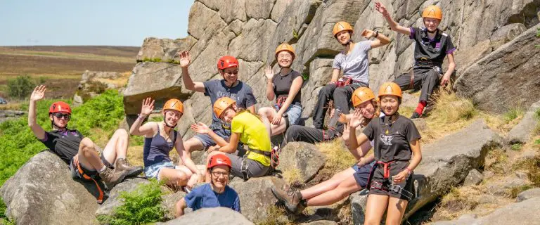 image of a group of students waving with hardhats and climbing gear