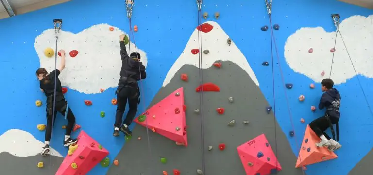 school group climbing up an outdoor climbing wall