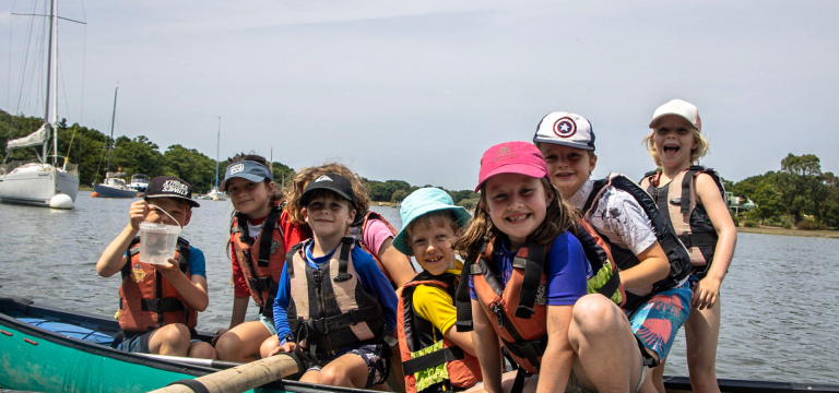 school pupils in a large group canoe on a river