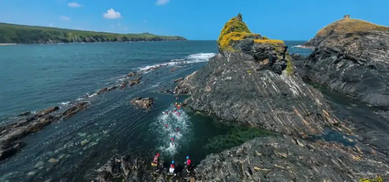 school group swimming in the sea next to rocks