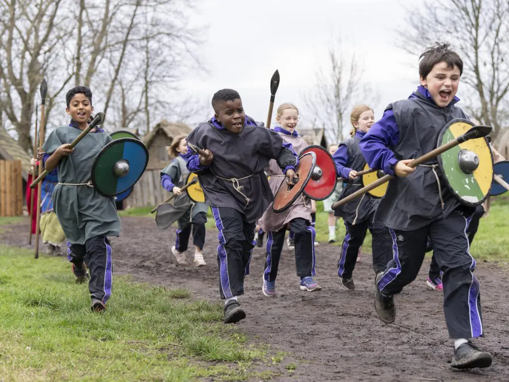 group of school children dressed in Saxon clothes running with shields and spears