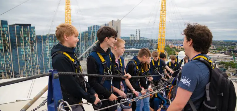 school group standing on top of the O2 in London with safety equipment attached to a safety line