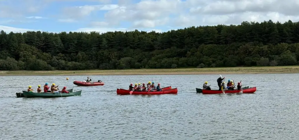 image of six boats of students rowing in teams on a lake