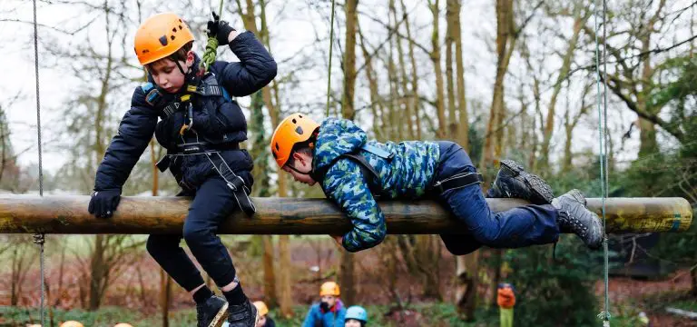 two school students on a wooden beam high up