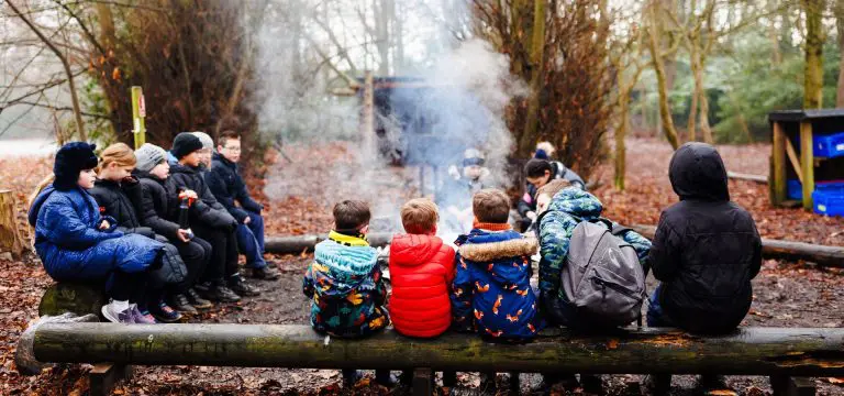 school group around a fire pit in the forest