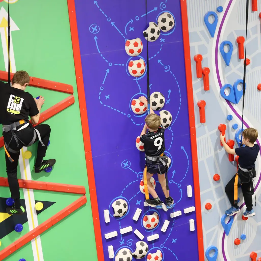 three pupils all on a climbing wall high up