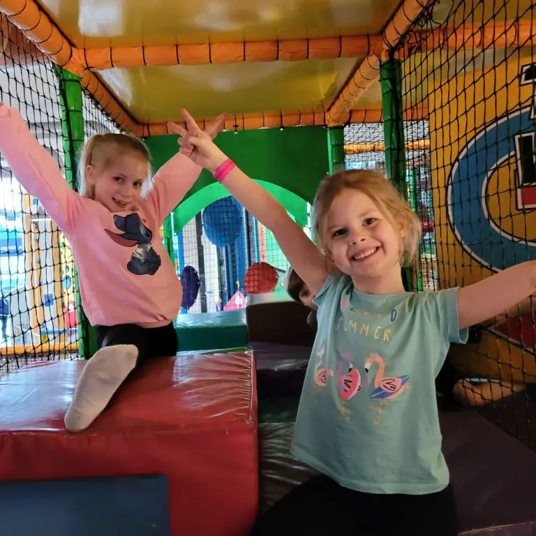 two primary school children play on an indoor adventure centre