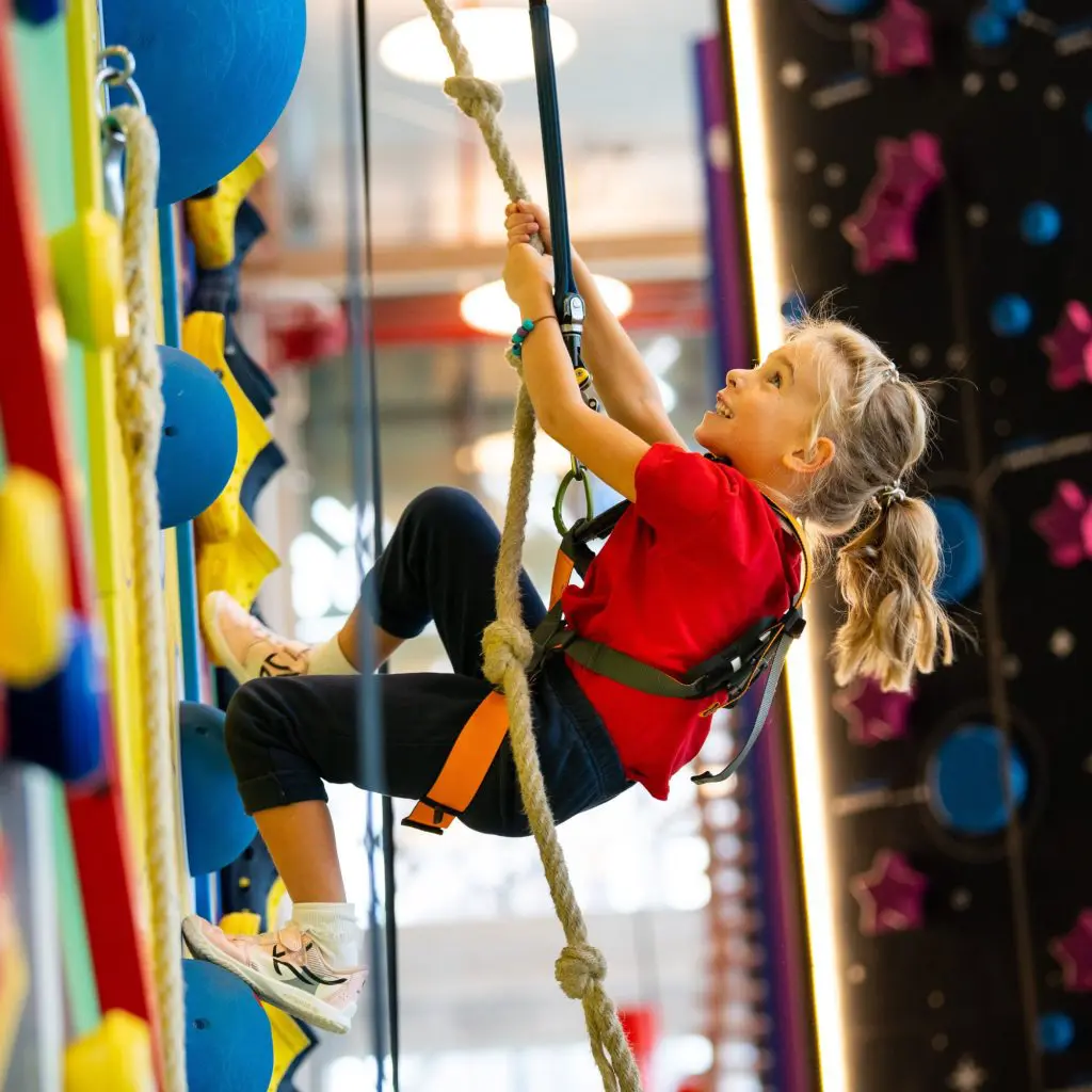 primary school pupil with safety harness and ropes abseiling