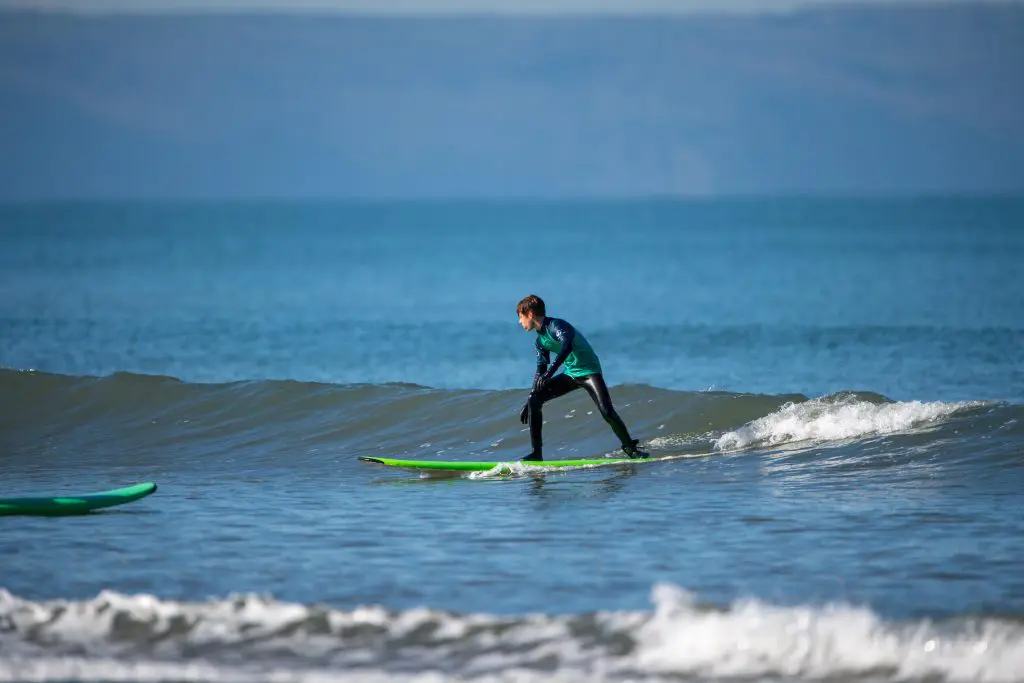 student surfing on a wave at the coast