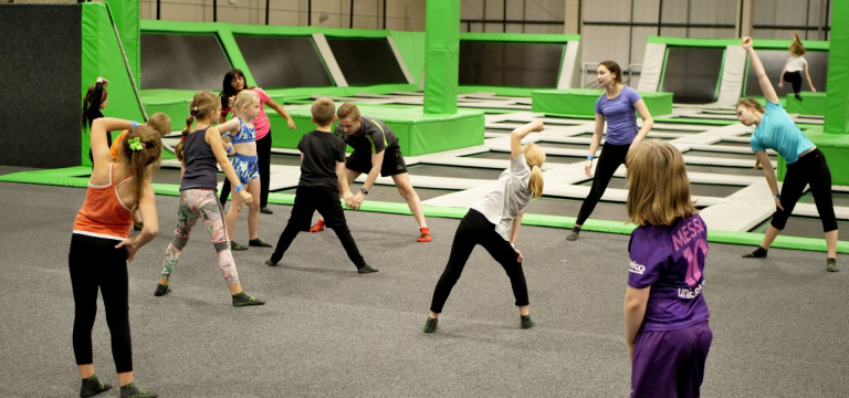 school group strecthing with trampoline instructor