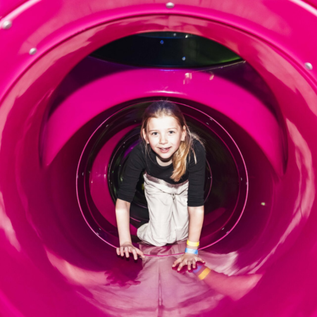 school pupil crawling through a tunnel in a soft play area
