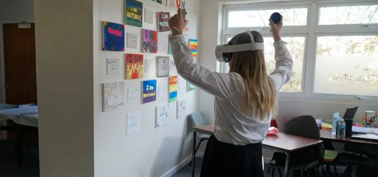 secondary school pupil with 4D immersive face masks and hand control sticks in classroom