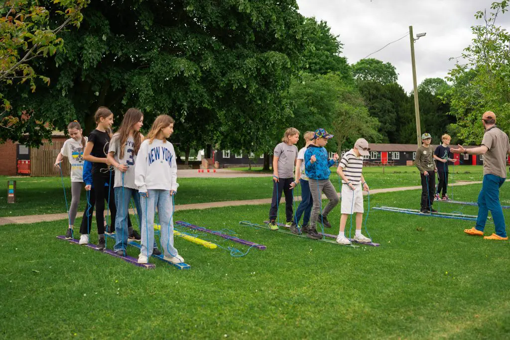 group of school trip pupils in a field doing team challenges