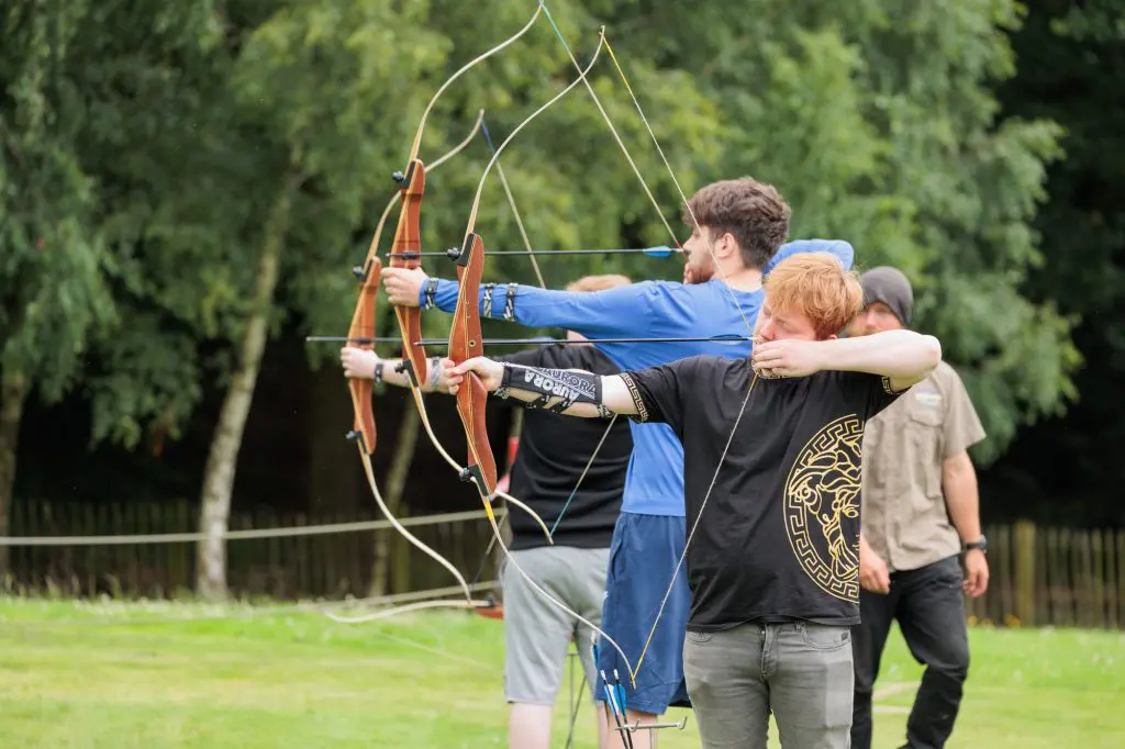a group of pupils on a school trip doing archery