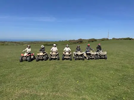7 students on quad bikes in a field