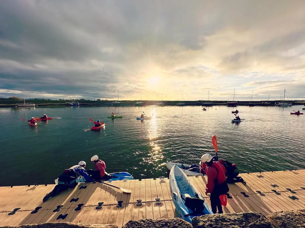 students on single kayaks on a lake in Wales
