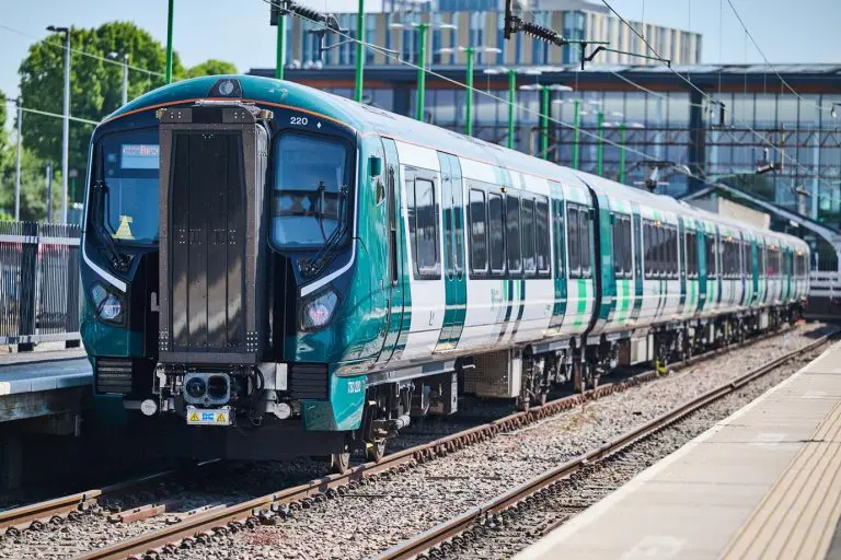 four carriage train stopped at a city centre station