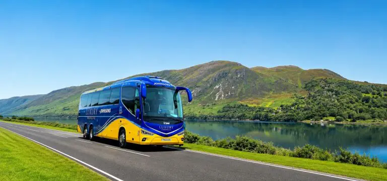 coach driving by a lake in the countryside