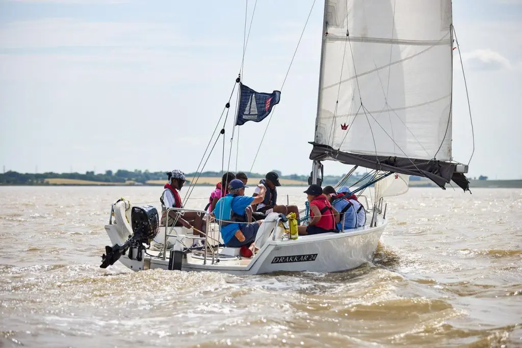 Essex Outdoors Bradwell Water Sports and Adventure Activity Residential School Trips 5 pupils aboard a sailing boat on a large river inlet