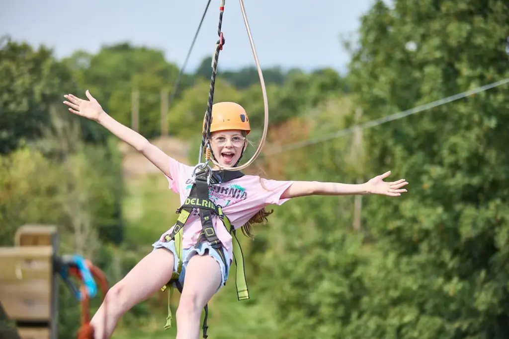 school pupil on a zip wire waving and smiling