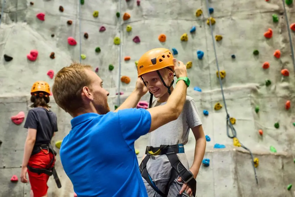 Essex Outdoors Harlow Adventure Activity Days 7 school pupil with safety gear with hard hat ready to climb an outdoor climbing wall