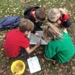 school group in a field doing nature tests