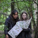 pupils holding nature map in a wood
