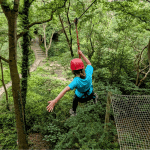 pupil going down a zip line in a wooded forest