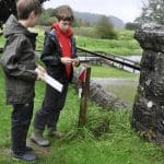 two school students outside with a map in the country