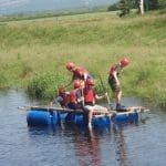 school group with lifejackets hard hats on a raft in a lake in Cumbria