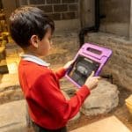primary school child looking at an audio book at the Roman Baths